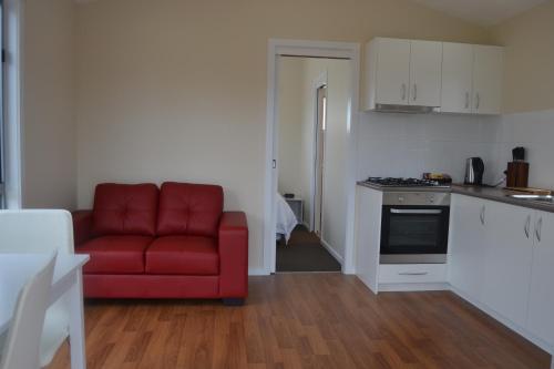 a living room with a red couch and a kitchen at Portland Holiday Village in Portland