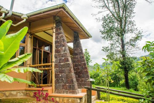 a house with a stone pillar in front of it at Ichumbi Gorilla Lodge in Kisoro