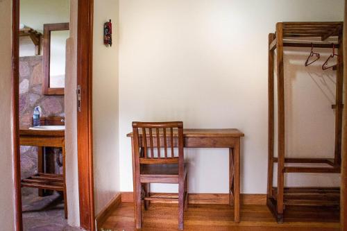 a room with a table and a chair and a mirror at Ichumbi Gorilla Lodge in Kisoro
