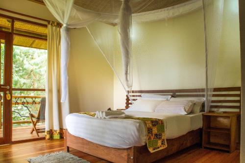 a bedroom with a canopy bed with a porch at Ichumbi Gorilla Lodge in Kisoro