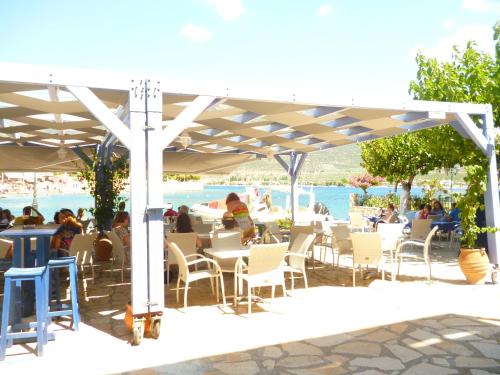 a group of people sitting at tables under a white umbrella at Boutique Hotel Iasmos in Trizonía