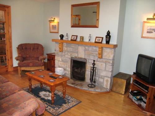 a living room with a stone fireplace and a television at Holiday Home Glenvale Cottage by Interhome in Valley