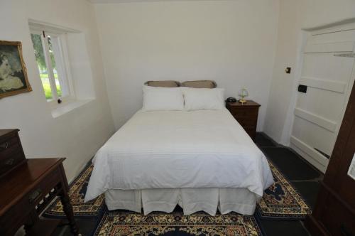 ein Schlafzimmer mit einem weißen Bett und einem Fenster in der Unterkunft Peppermint Farm Cottage in McLaren Vale