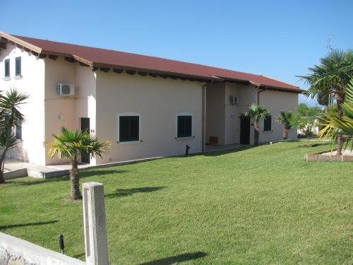 a building with palm trees in front of a yard at Residence IL Villaggio del Re in Corropoli