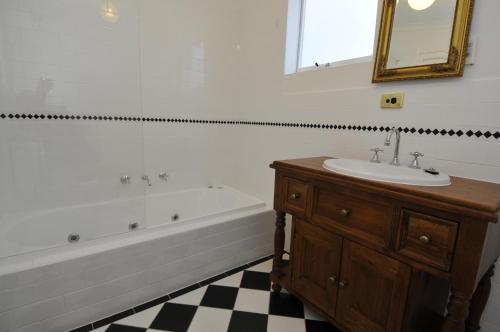 een badkamer met een wastafel, een bad en een spiegel bij Peppermint Farm Cottage in McLaren Vale