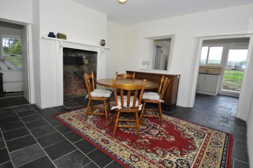 a dining room with a table and chairs and a rug at Peppermint Farm Cottage in McLaren Vale