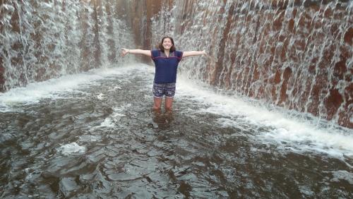 a woman standing in the water near a waterfall at Disna Homestay in Habarana