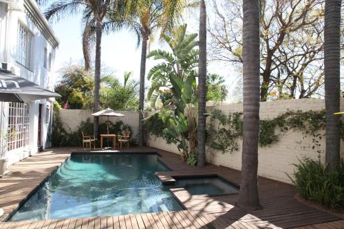 a swimming pool in a backyard with a table and chairs at Village Ridge Boutique Stays in Pretoria