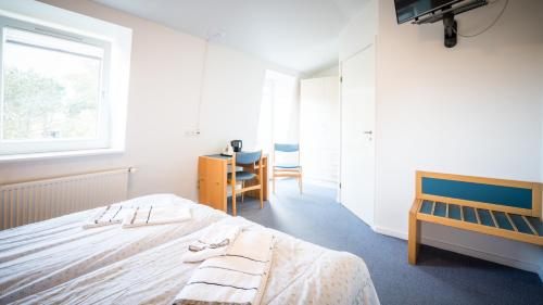 a bedroom with a bed and a desk and a window at Hotel Havlund Bed and Breakfast in Grenå