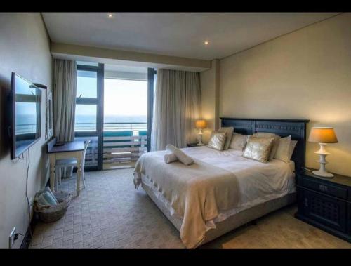 Dormitorio con cama, escritorio y TV en The Pearls of Umhlanga - Ocean view Apartments, en Durban