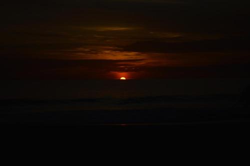 a sunset in the clouds with the sun in the background at Whitepearl Beach in Hikkaduwa