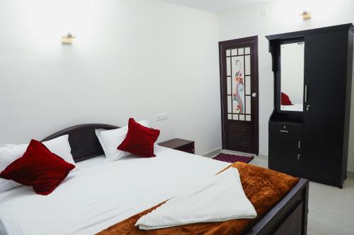 a bedroom with a bed with red and white pillows at Green Garden Wayanad Villas in Vayittiri