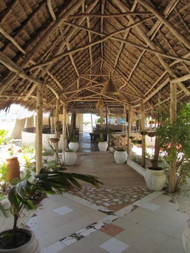 a large wooden pavilion with a lot of plants at Driftwood Beach Lodge in Jambiani