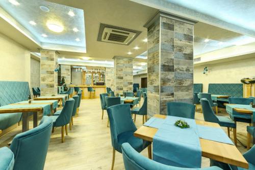 a restaurant with wooden tables and blue chairs at SPA Hotel Infinity Park Velingrad in Velingrad