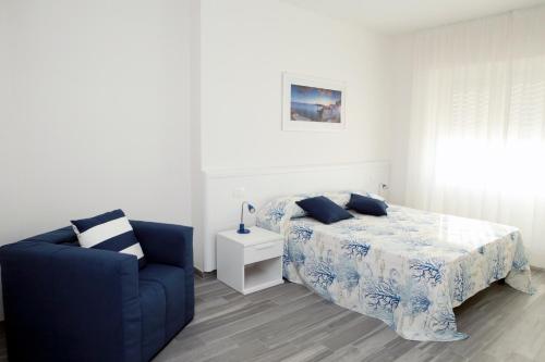 a bedroom with a bed and a blue chair at La Marina B&B in Civitavecchia