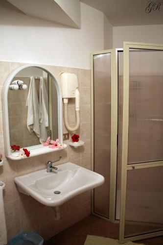 a bathroom with a sink and a shower and a mirror at Hotel L'Ancora in Capo Vaticano