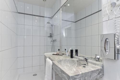 a white bathroom with a sink and a shower at Hotel du Pré in Paris