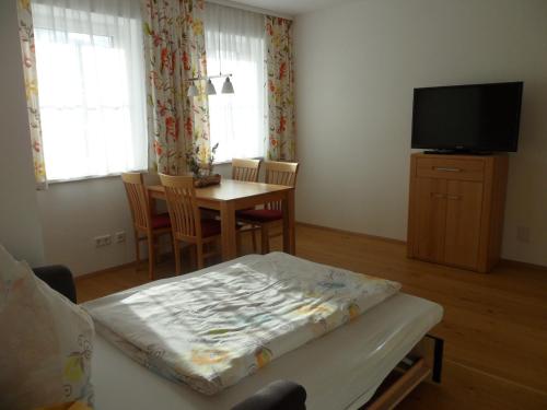 a living room with a table and a tv at Appartement Alpenglück in Aich