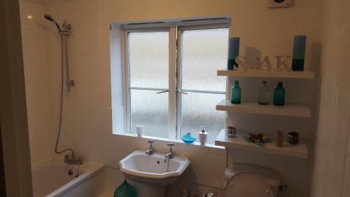 a bathroom with a sink and a toilet and a window at Haus Serviced Living in Braintree