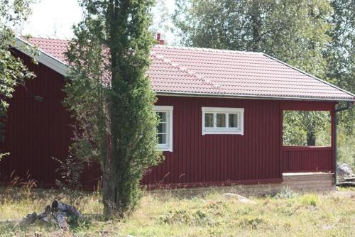 een rood huis met een boom ervoor bij Grönelid Gård in Tived