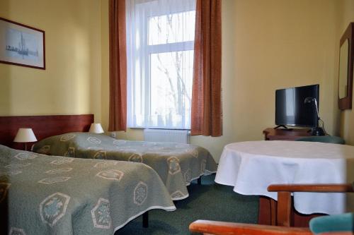 シュチェチンにあるHotel Kapitanのベッド2台と窓が備わるホテルルームです。