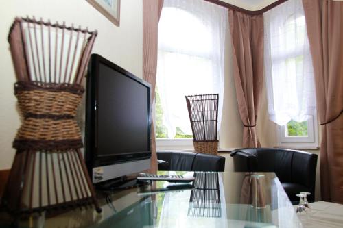 a living room with a glass table with a television at Hotel Schober am Kurpark in Bad Salzschlirf