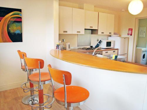 a kitchen with a bar with orange chairs in it at Holiday Home Grove Lodge-2 by Interhome in Killorglin