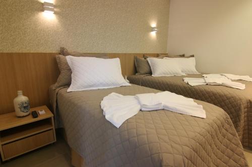 two beds in a hotel room with towels on them at Tupyguá Brasil Hotel in Pedro Leopoldo
