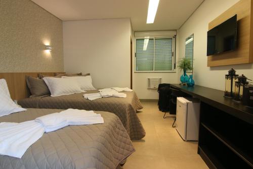 a hotel room with two beds and a television at Tupyguá Brasil Hotel in Pedro Leopoldo