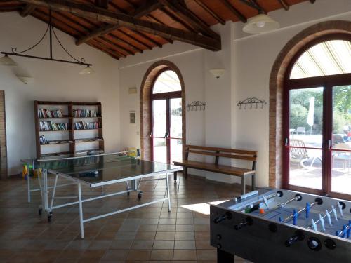 two ping pong tables in a room with windows at Borgo Sicelle Residence in San Donato in Poggio
