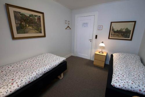 a bedroom with two beds and a lamp on a table at Hotel Lolland in Nørreballe