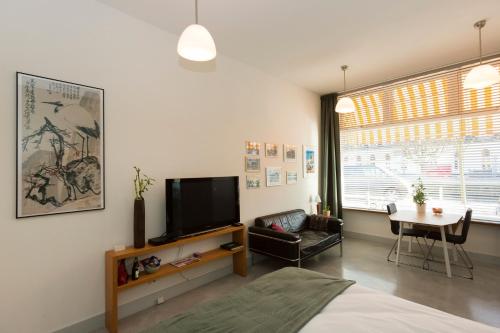 een woonkamer met een bed, een tv en een tafel bij VeenkadeBnB in Den Haag