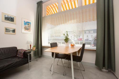 een eetkamer met een tafel en een groot raam bij VeenkadeBnB in Den Haag