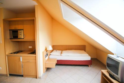 Hotel Ferchenhof في ميونخ: غرفة صغيرة بها سرير ومطبخ