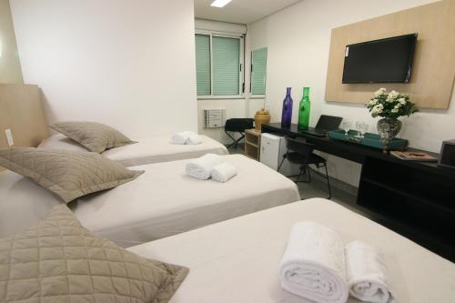 a bedroom with two beds and a desk with a television at Tupyguá Brasil Hotel in Pedro Leopoldo