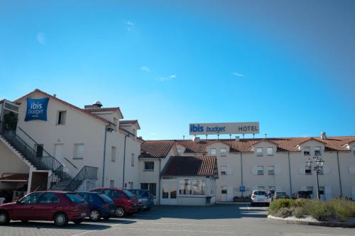 a row of buildings with cars parked in a parking lot at Ibis Budget Agen in Le Passage