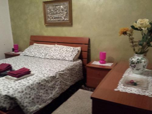 1 dormitorio con 1 cama y un jarrón con flores sobre una mesa en La via per Milano, en Vigevano