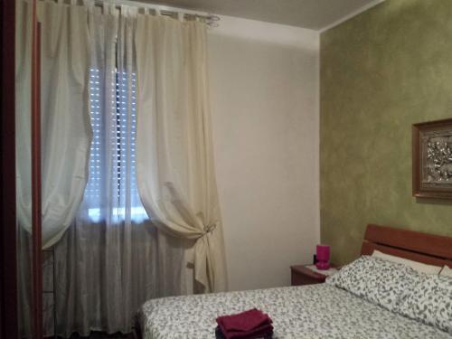 a bedroom with two beds and a window with curtains at La via per Milano in Vigevano