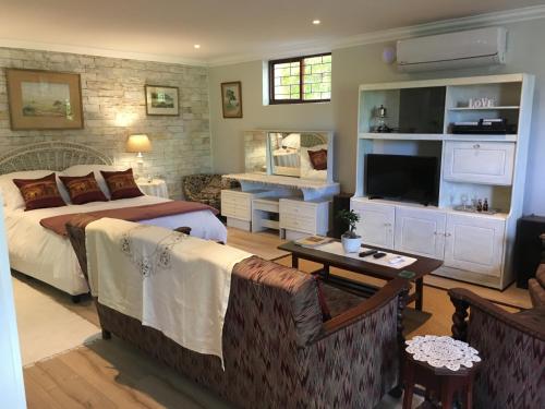 a bedroom with a bed and a living room at Geranium Studio in Somerset West