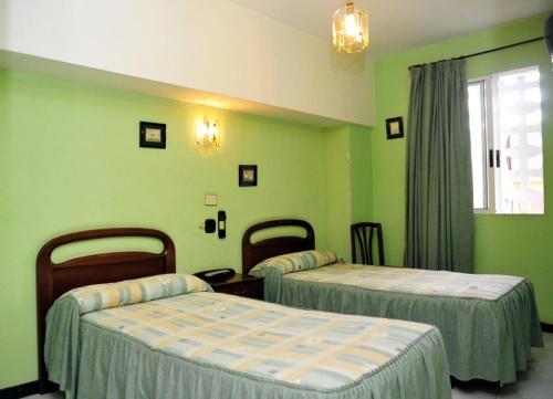 two beds in a room with green walls at Pensión Ariz in Basauri