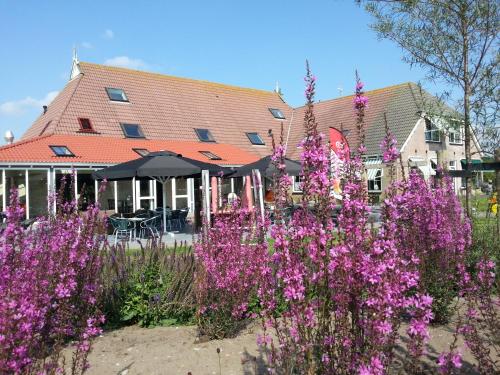 a garden with purple flowers in front of a building at Bed and Breakfast De Zeehoeve in Harlingen