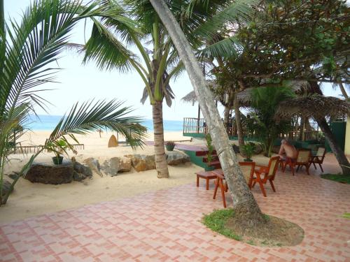a table and chairs on the beach with palm trees at Whitepearl Beach in Hikkaduwa