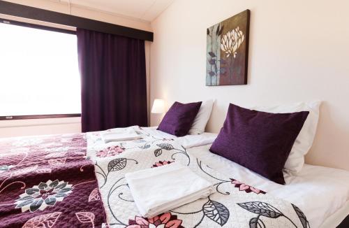 a bedroom with a bed with purple pillows at Hotel Julie in Joensuu