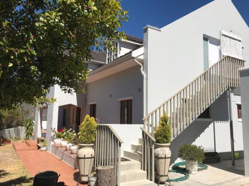 a white house with stairs and potted plants at The Loft in Hout Bay