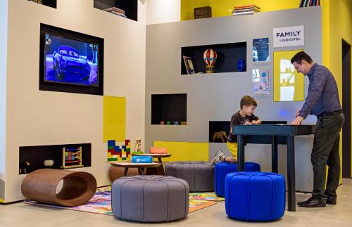 a man and a boy standing at a table with a laptop at Novotel Sorocaba in Sorocaba