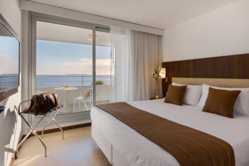 a bedroom with a bed and a balcony with the ocean at Dazzler by Wyndham Colonia in Colonia del Sacramento