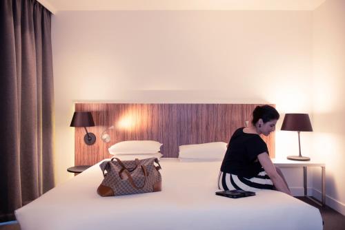 a woman sitting on a bed in a hotel room at Mercure Hotel Nijmegen Centre in Nijmegen