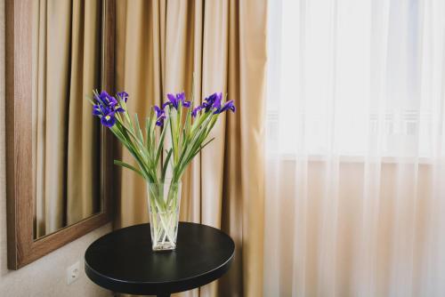 a vase with purple flowers sitting on a table at Hotel Alkor in Truskavets