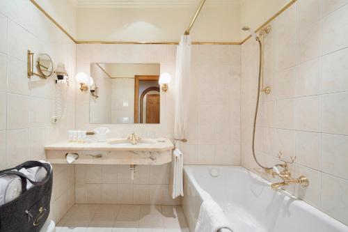 ein weißes Badezimmer mit einer Badewanne und einem Waschbecken in der Unterkunft Hotel Singer – Relais & Châteaux in Berwang