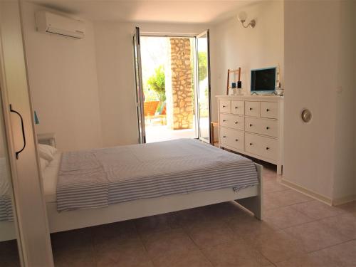 a bedroom with a bed and a dresser and a television at Studio Apartment Branko in Novalja